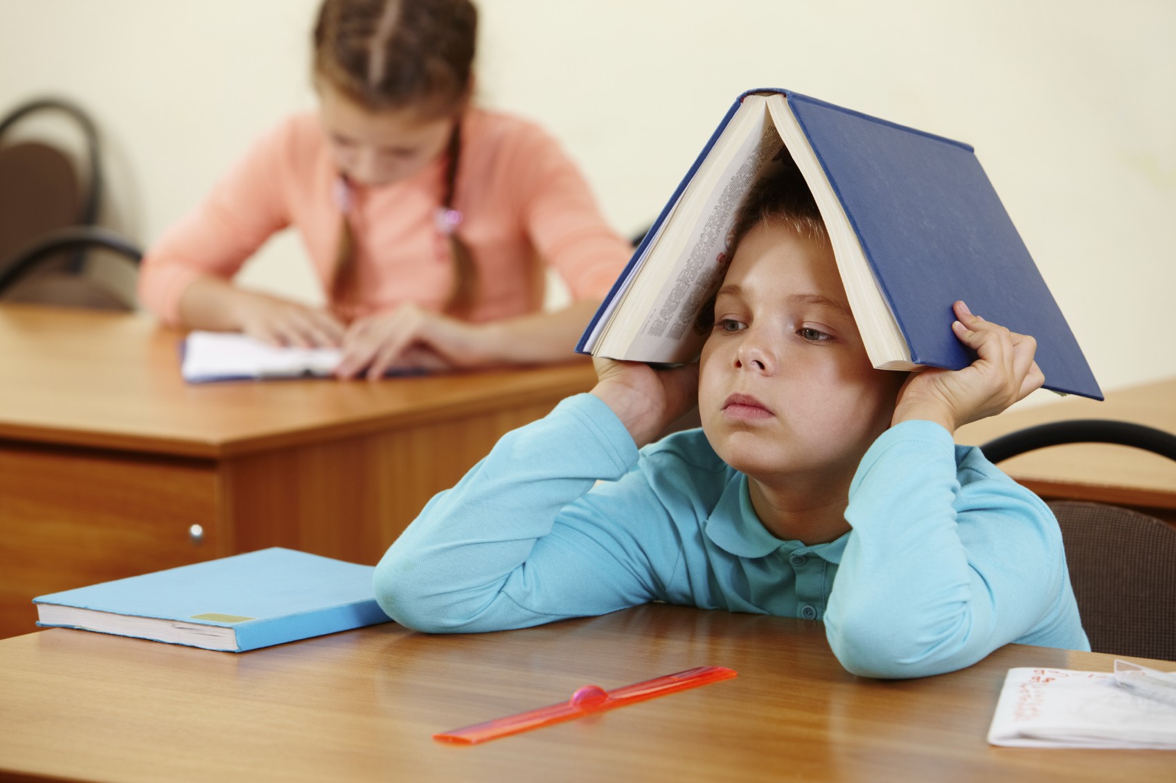 boy in class with book on head