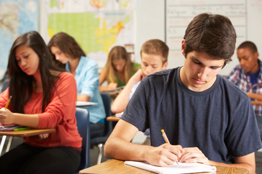 teen boy writing in class