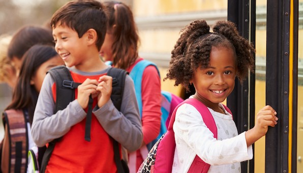 Smiling children boarding school bus