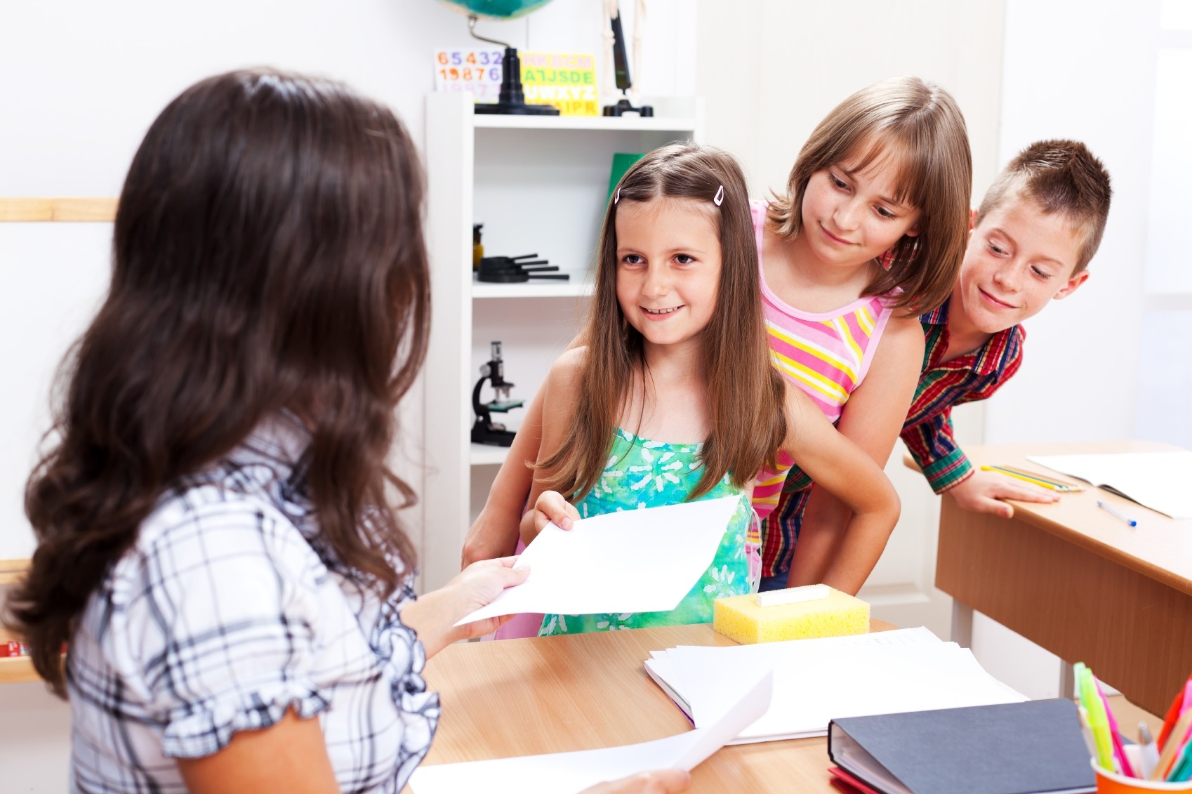 teachers passing out papers to kids in class