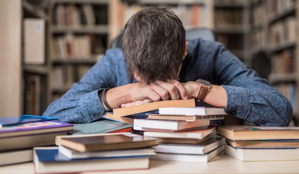 student with head on books