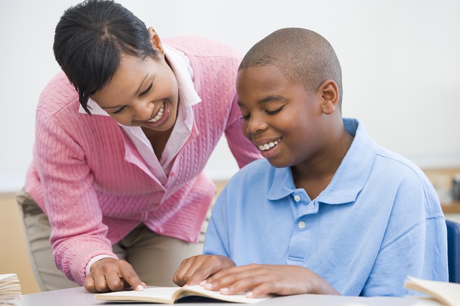 teen boy with teacher reading in school