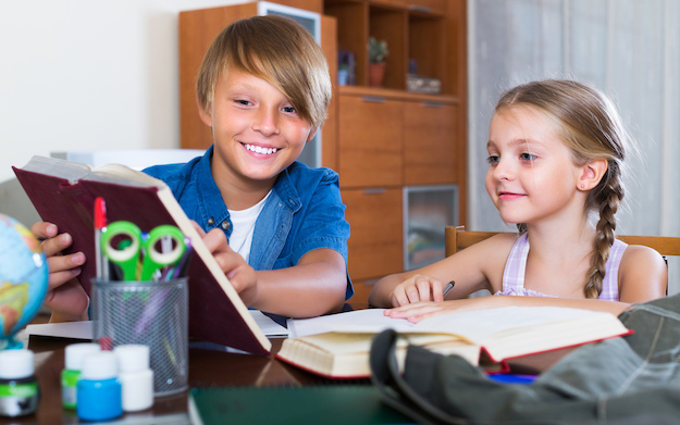 elementary school boy and girl smiling when looking at a book