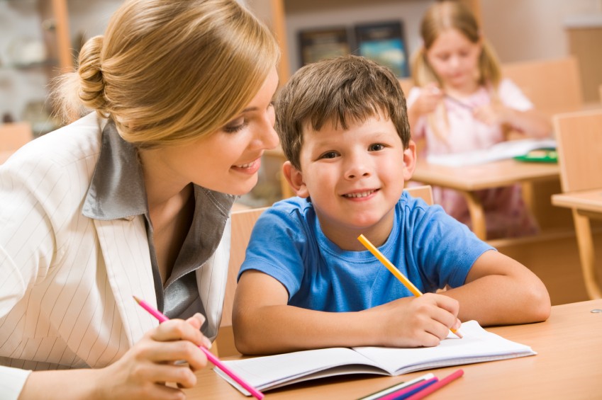 image of boy writing with tutor or evaluator