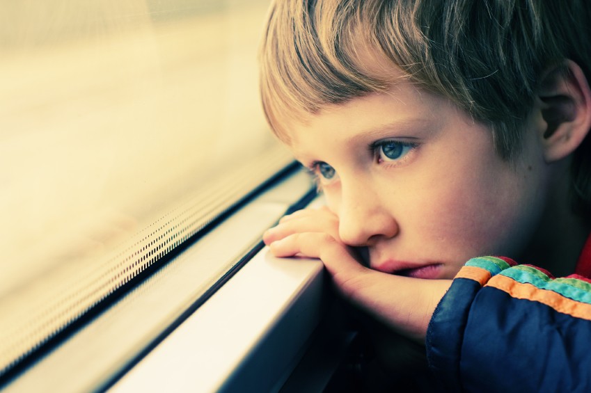 serious boy at the school bus window