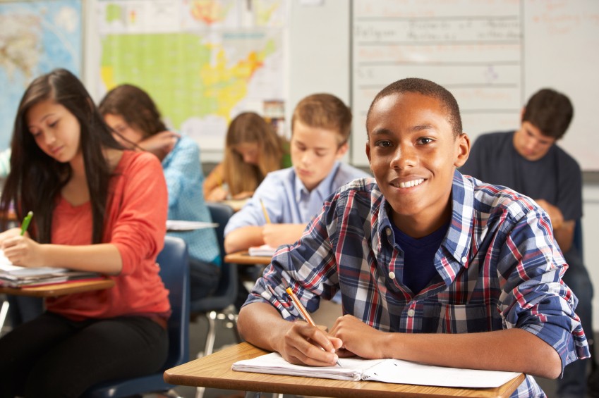 happy teen boy writing in school