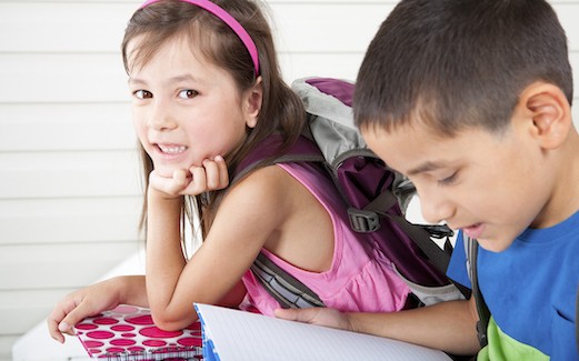 a girl and boy reading while sitting on a porch