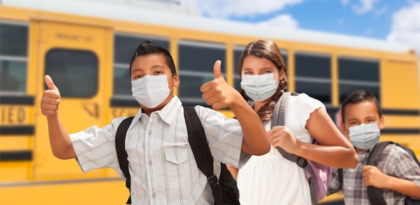 3 children standing in front of school bus