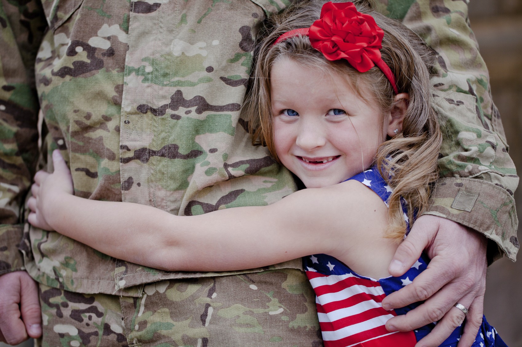 young girl hugging military dad