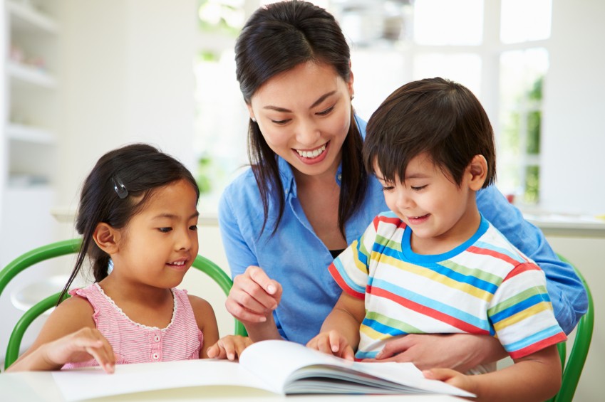 image of mom with two young children doing school work