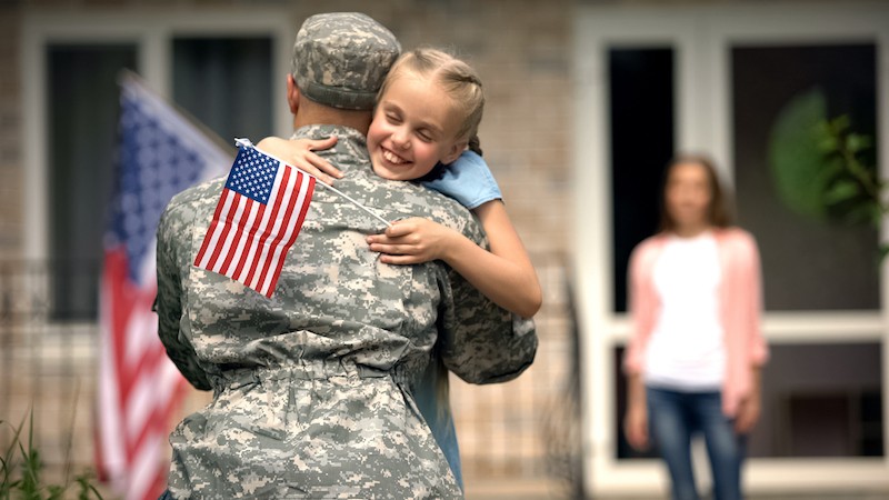 image of soldier dad with daughter and flag