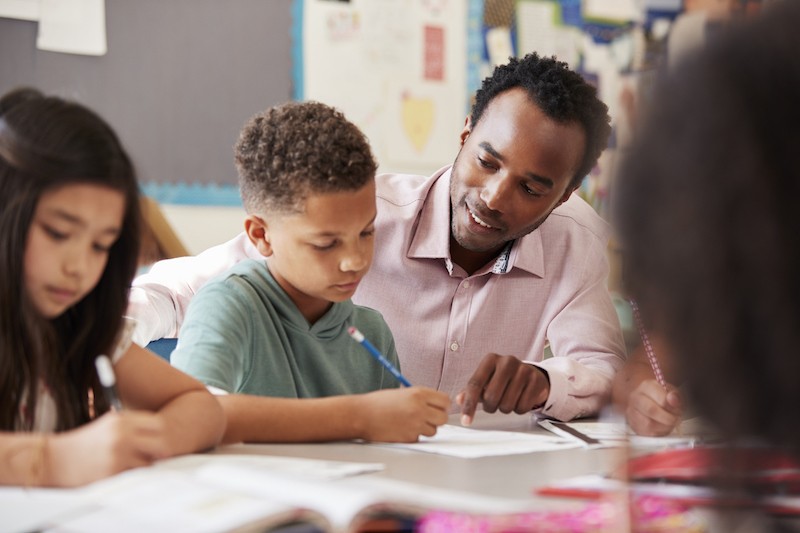 image of teacher helping students