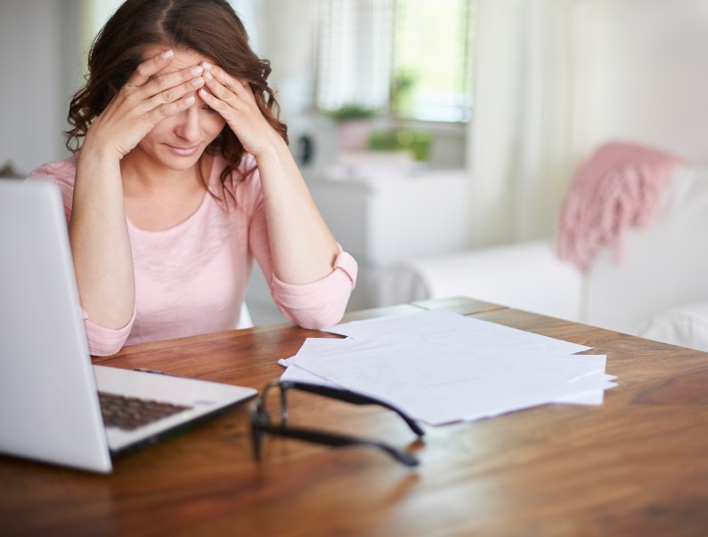 image of frustrated mom at computer with papers