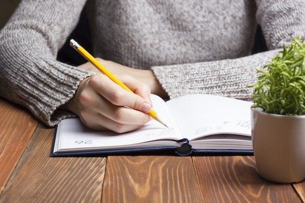 hands of a woman writing in a journal