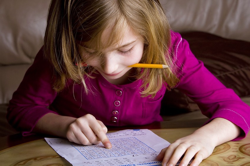 girl writing math paper at school